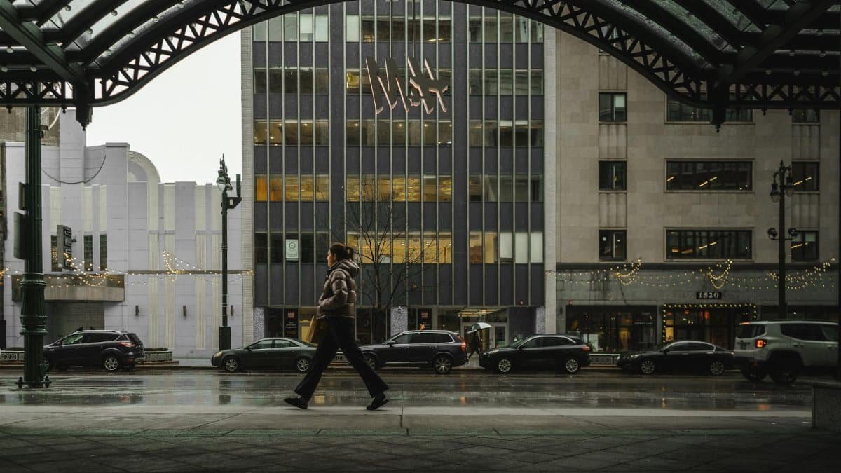 A person walks in downtown Detroit, MI, showcasing urban life amidst rain and city lights.