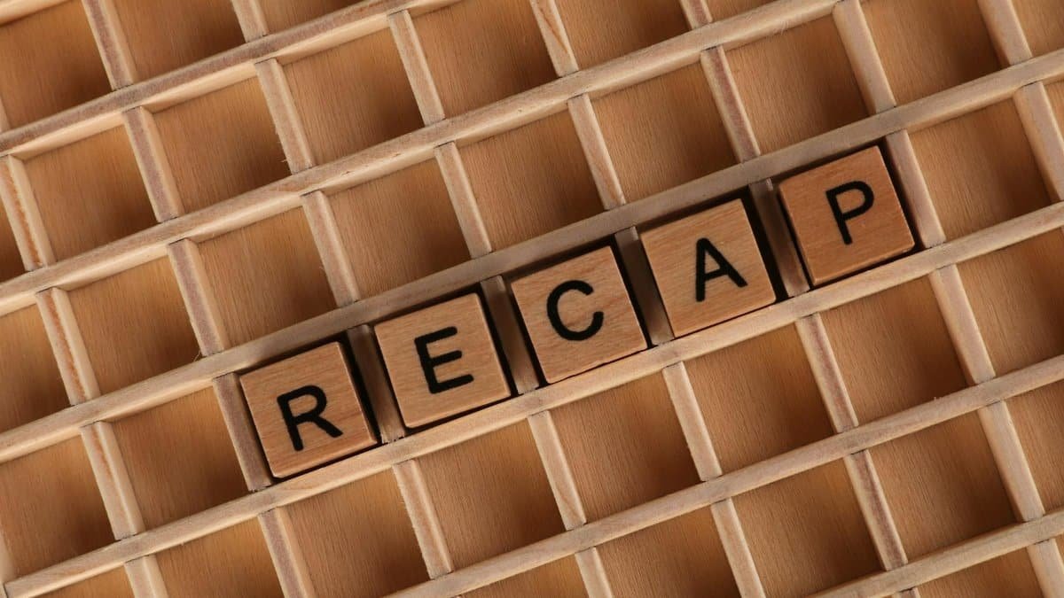Close-up of wooden letter tiles spelling 'Recap' on a wooden grid pattern.