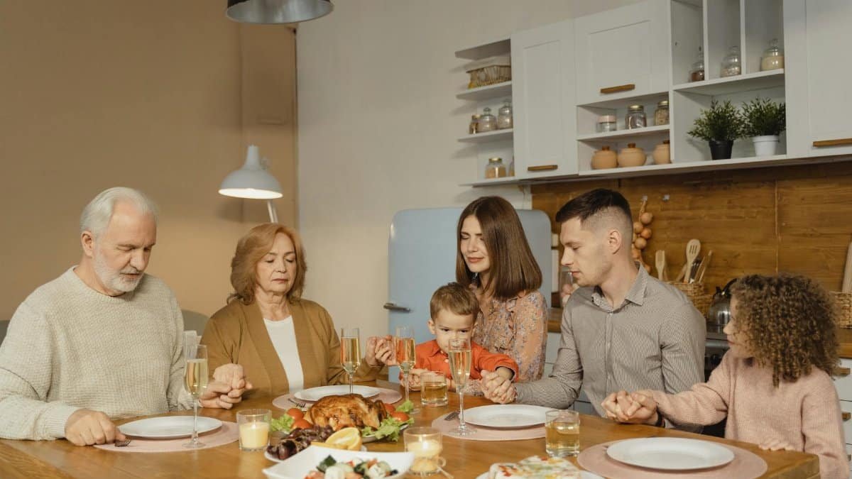 A family gathers for a heartfelt prayer before enjoying a festive meal.