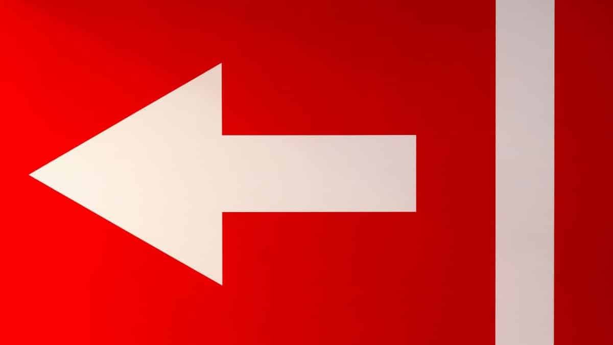 White arrow pointing left on a bold red background, symbolizing direction.