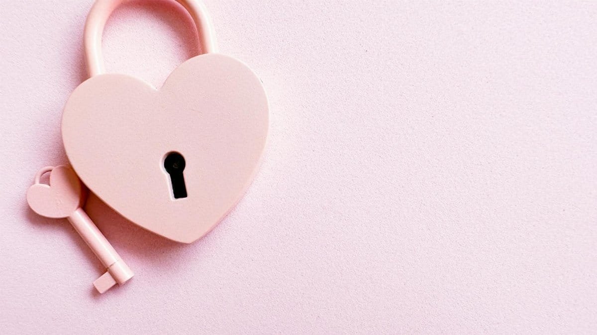 Aesthetic photo of a heart-shaped pink padlock with a matching key on a pink background, perfect for love themes.