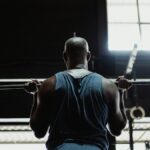 A muscular man lifting a barbell indoors, showcasing strength and fitness.