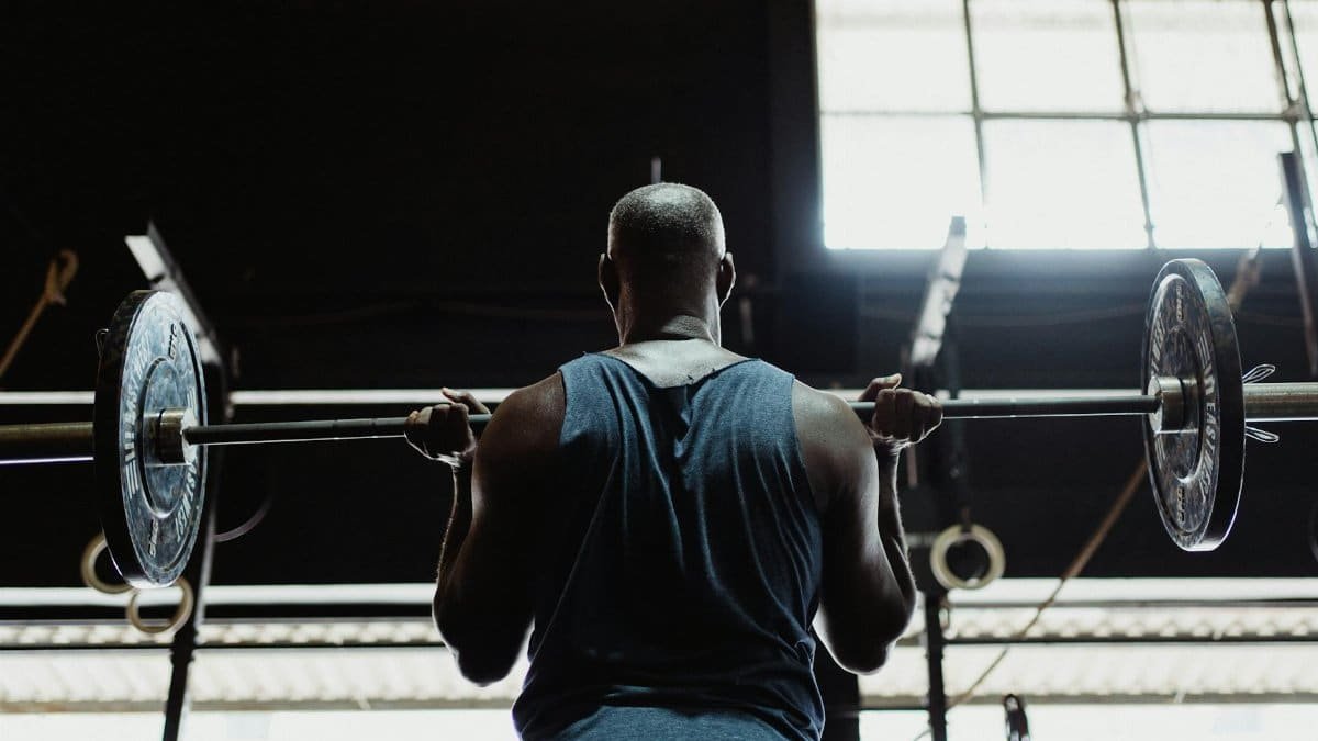 A muscular man lifting a barbell indoors, showcasing strength and fitness.