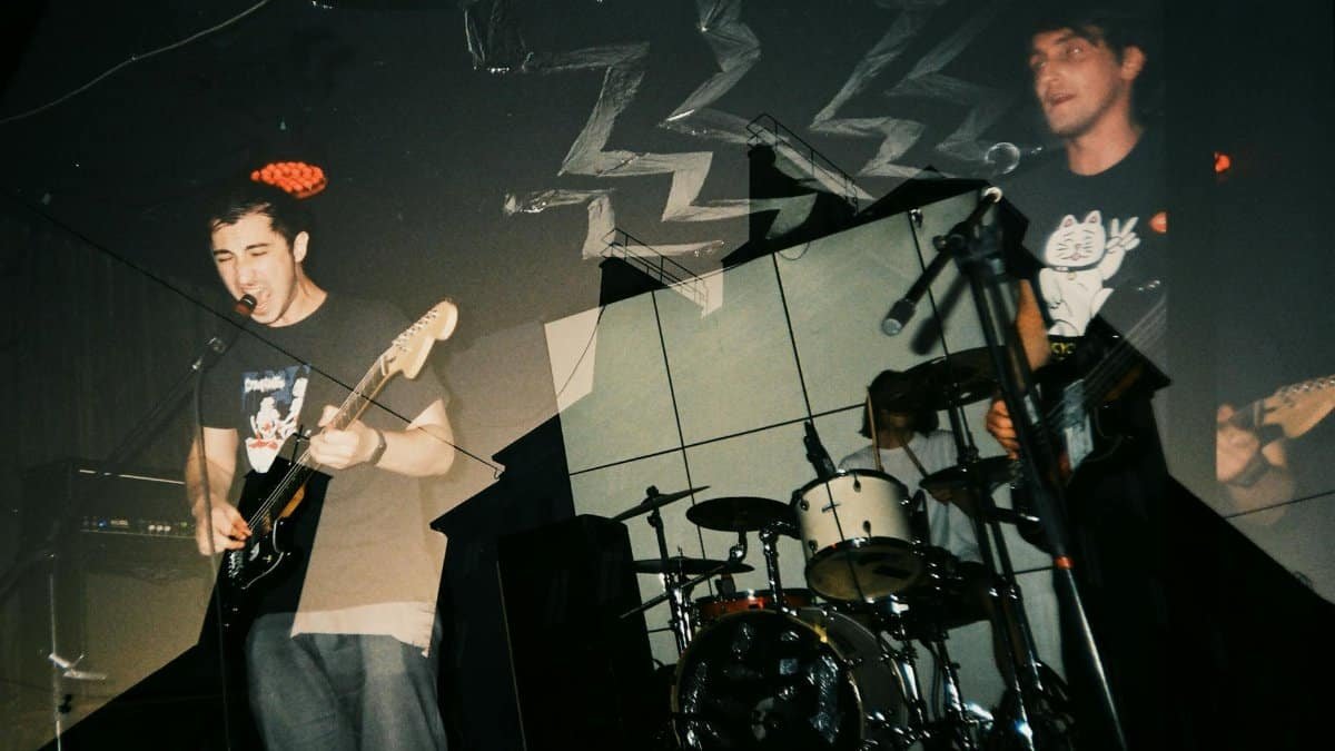 Energetic live performance captured with a double exposure, featuring a singer and guitarist on stage.