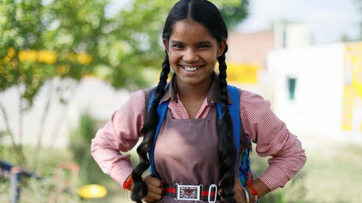 Happy student posing outdoors with a bright smile and school bag.