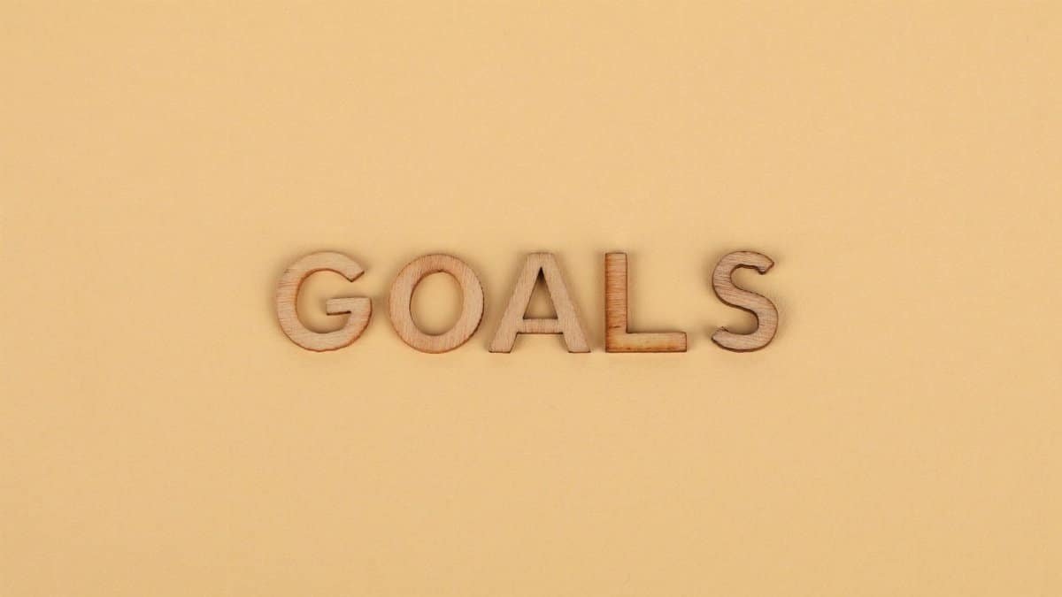 Wooden letters spelling 'GOALS' on a plain background, emphasizing motivation.