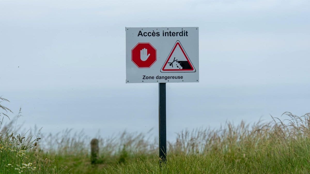 Sign saying 'Accès Interdit' in a grassy area, warning of a dangerous zone.