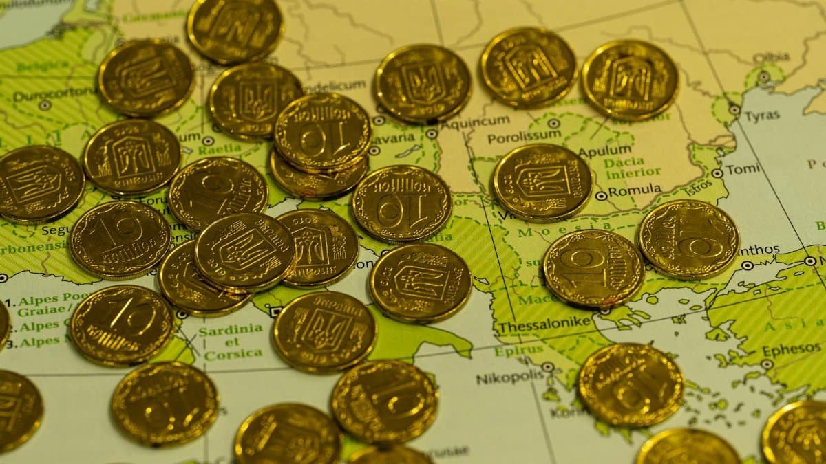 Pile of gold coins placed on top of a detailed geographical map.