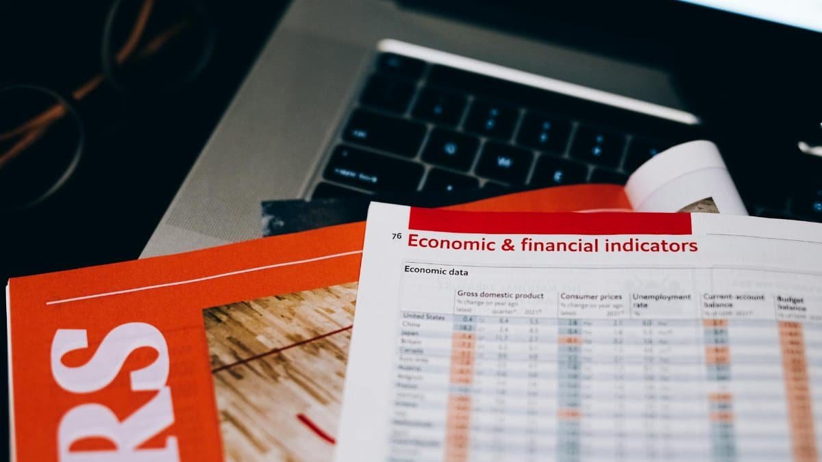 Detailed close-up of economic and financial documents on a laptop keyboard, highlighting data analytics.