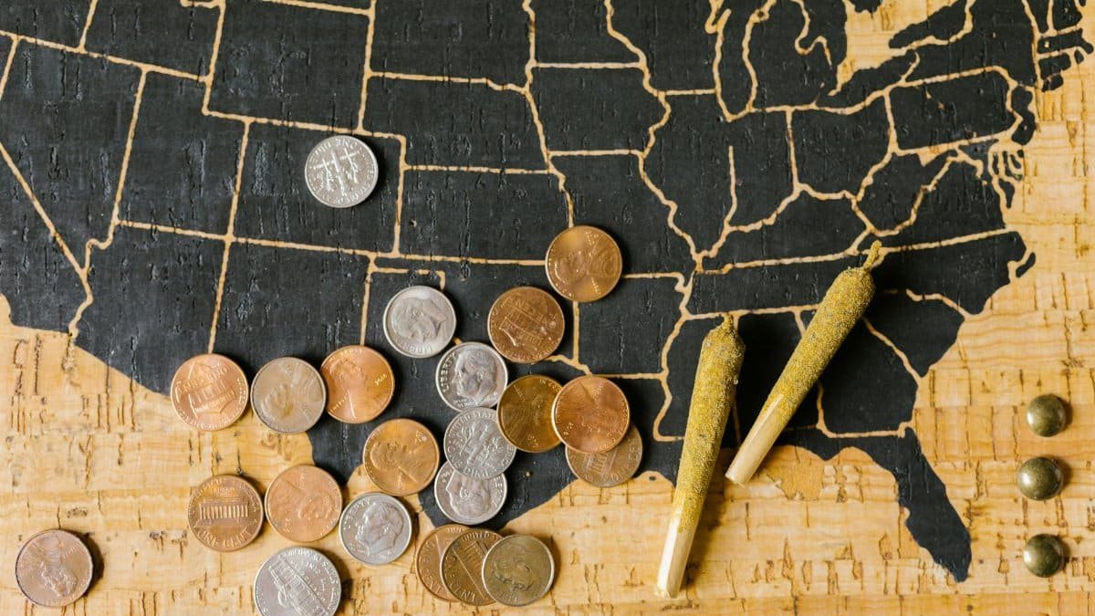 A USA map with cannabis joints and coins, symbolizing legal marijuana and its economic impact.