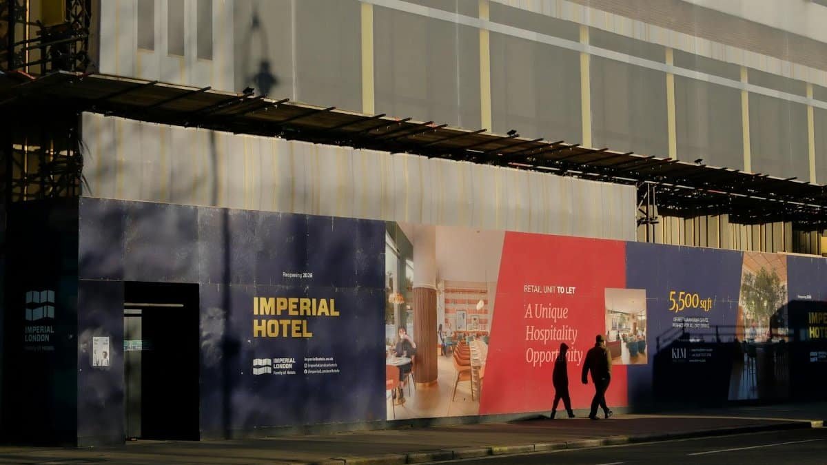 Construction site of Imperial Hotel in London with scaffolding and posters.