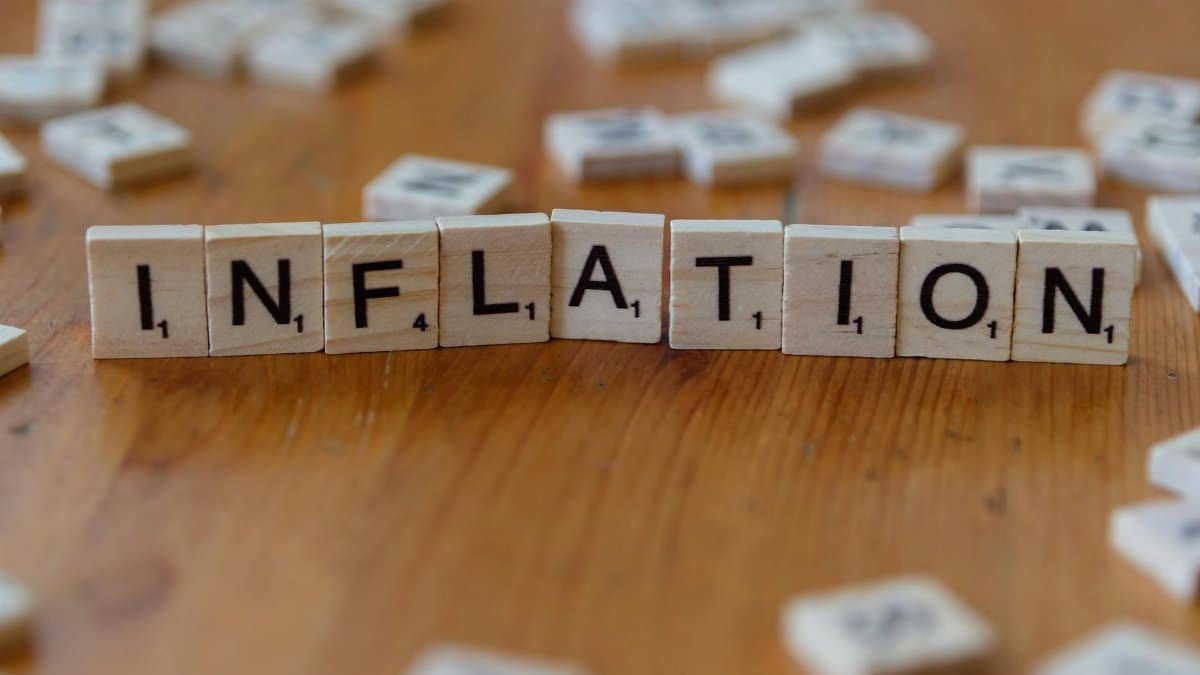 Scrabble letter tiles spelling 'INFLATION' on a wooden table, signifying economic concepts.