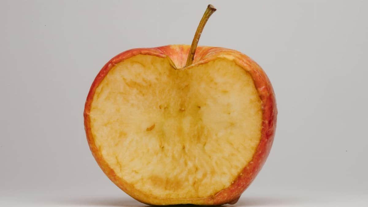 A halved apple with bite marks showcasing texture on a plain white background.