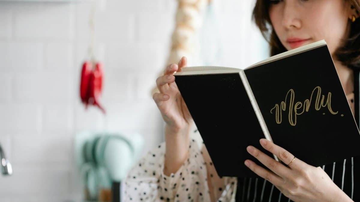 Close-up of a woman reading a menu indoors with a blurred cozy kitchen background.