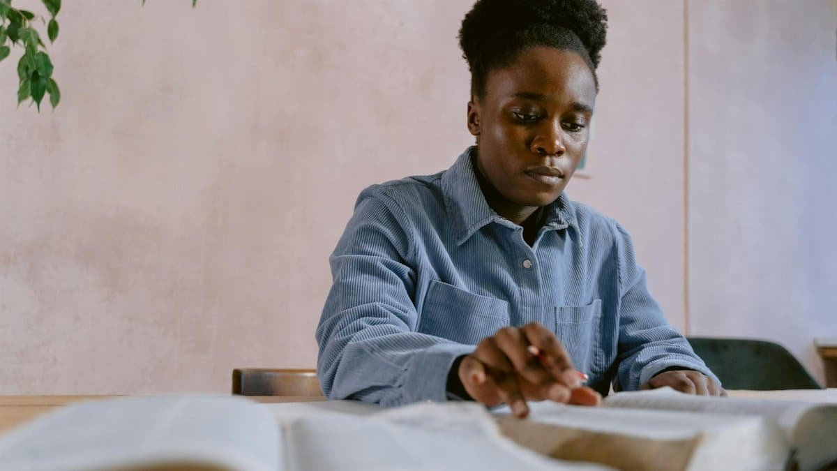 Focused woman reading and studying a Bible at a table indoors.