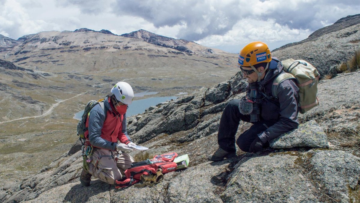 Two climbers navigate the rugged mountainous terrain using maps and equipment.
