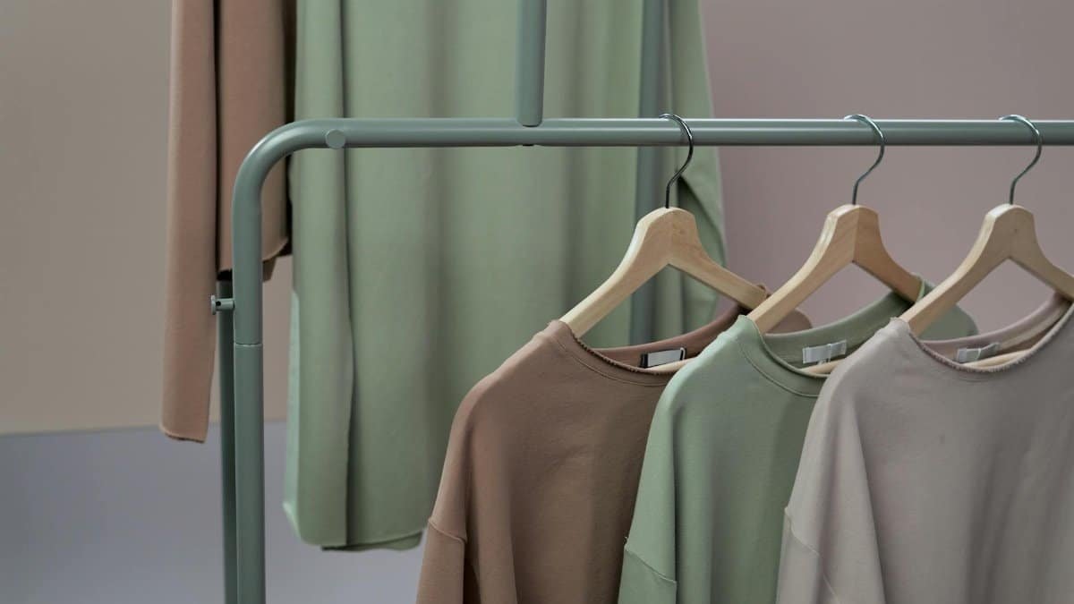 A stylish display of earth-toned sweaters on hangers in a studio setting.