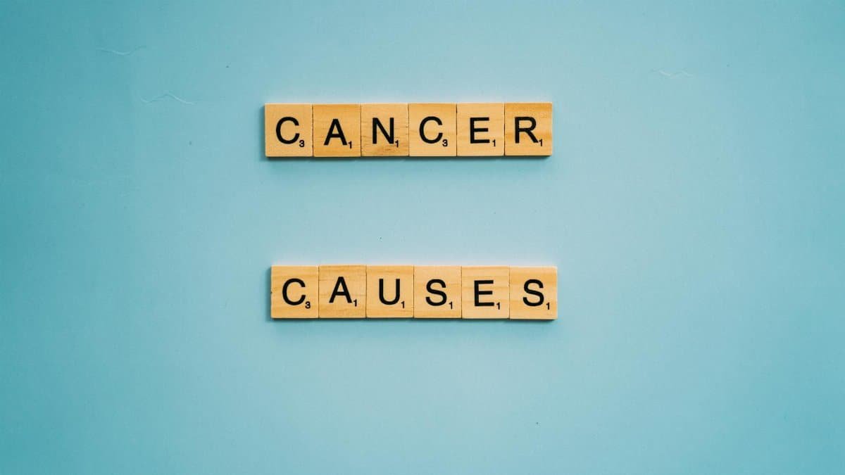Scrabble tiles spelling 'Cancer Causes' on a light blue background, highlighting awareness.
