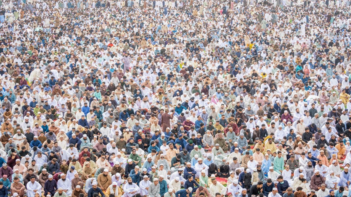 A massive crowd of people engaged in communal prayer, reflecting unity and spirituality.
