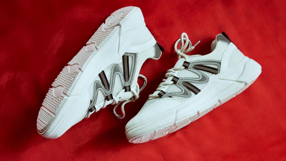 Stylish white sneakers showcased against a vibrant red backdrop, emphasizing contemporary design.