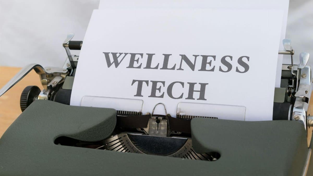 A close-up of a vintage typewriter featuring a paper with the words 'Wellness Tech.'