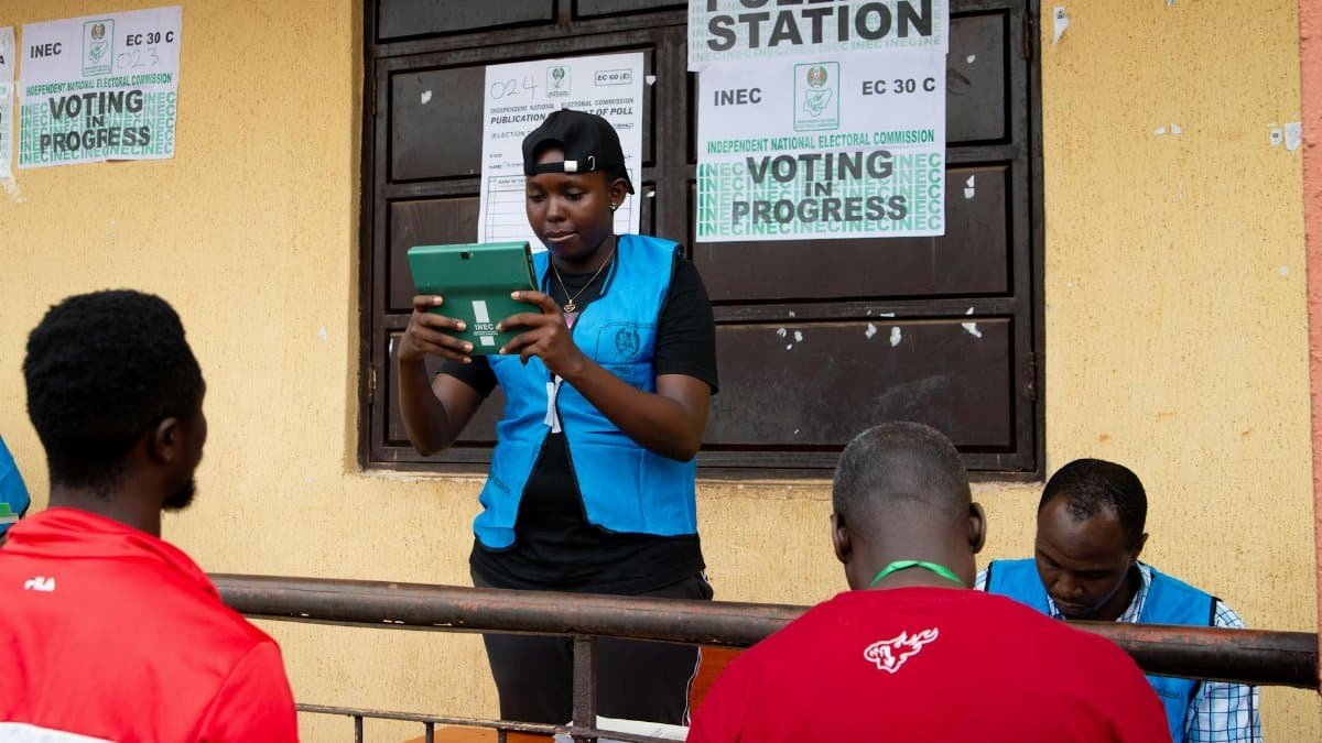 Election official in Nigeria assisting voters on election day at a polling station.