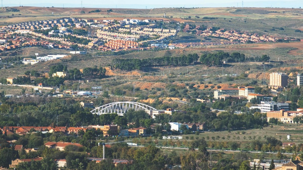 Aerial view showcasing Toledo's urban landscape surrounded by picturesque hills and greenery.