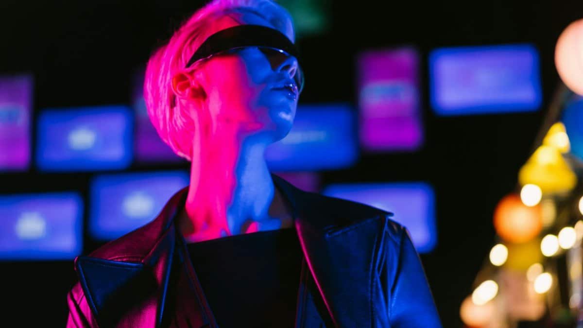 A woman in a leather jacket and sunglasses in a vibrant cyberpunk setting with neon lights.