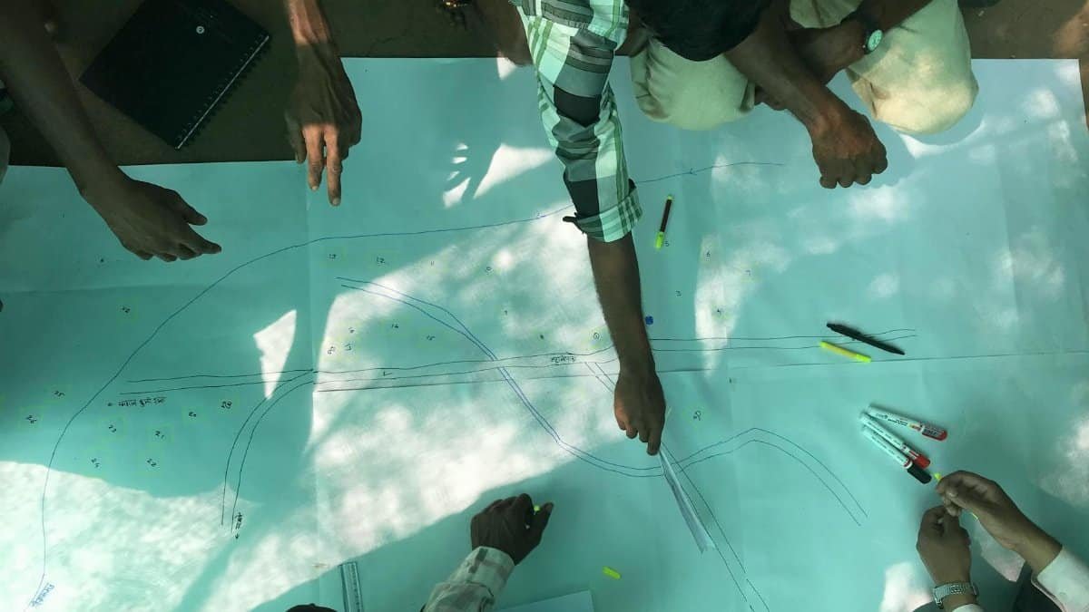 Group planning road design with drawings and tools outdoors.