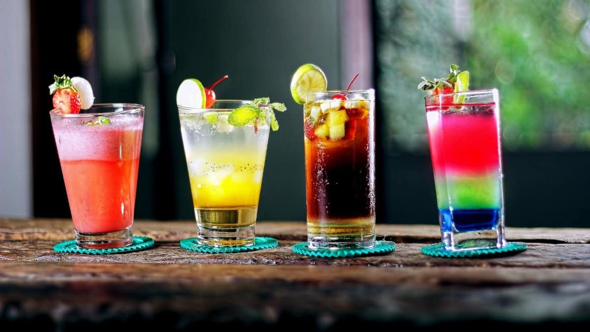 Colorful assortment of cocktails on a rustic wooden table, perfect for a refreshing summer evening.