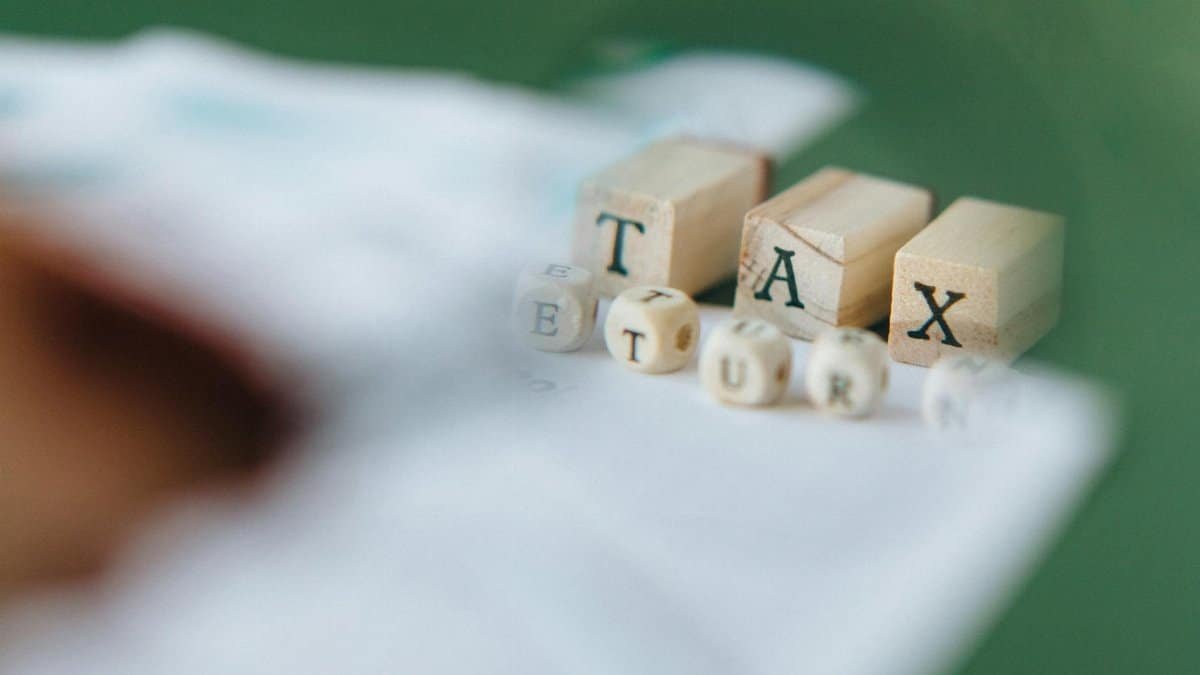 Wooden blocks and dice spelling 'Tax Return' on a blurred green background.