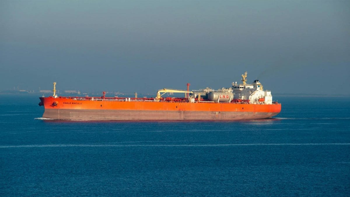 Bright orange LNG carrier ship cruising through calm sea waters on a clear day.