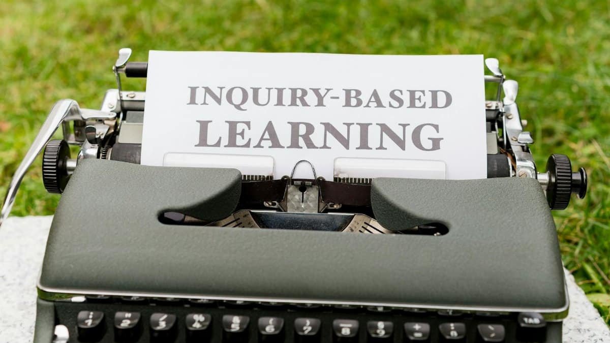 Close-up of a vintage typewriter with paper labeled 'Inquiry-Based Learning' outdoors.