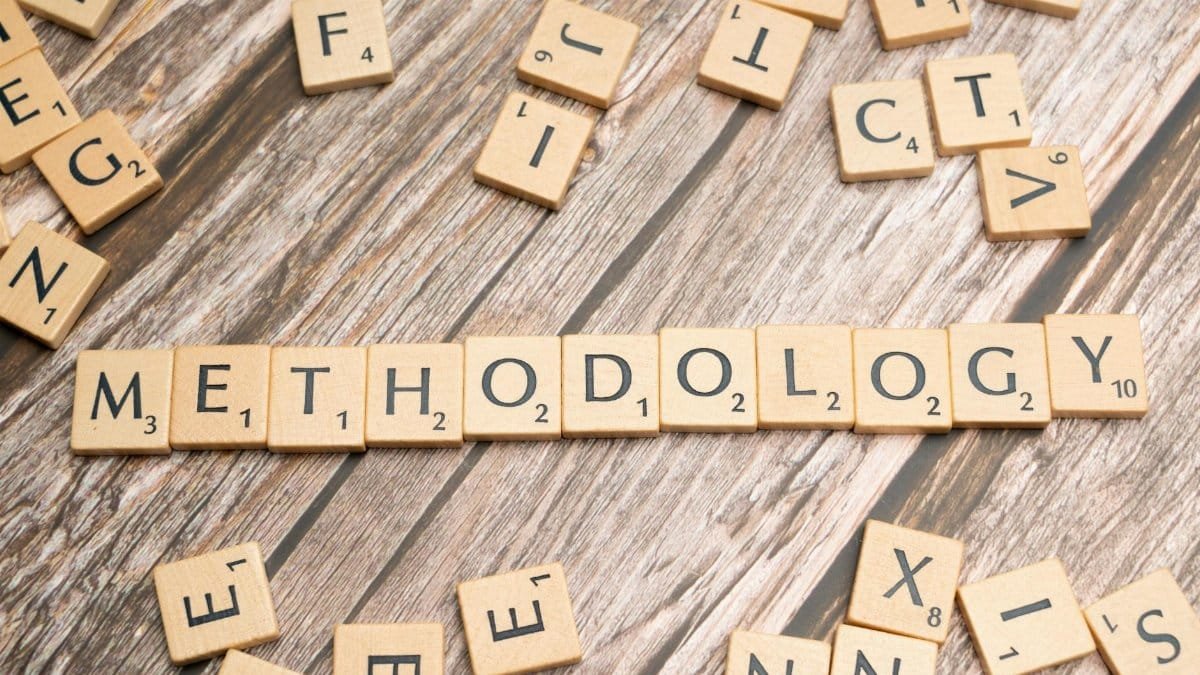 Wooden letter tiles spelling 'methodology' on a textured wooden surface, emphasizing research.