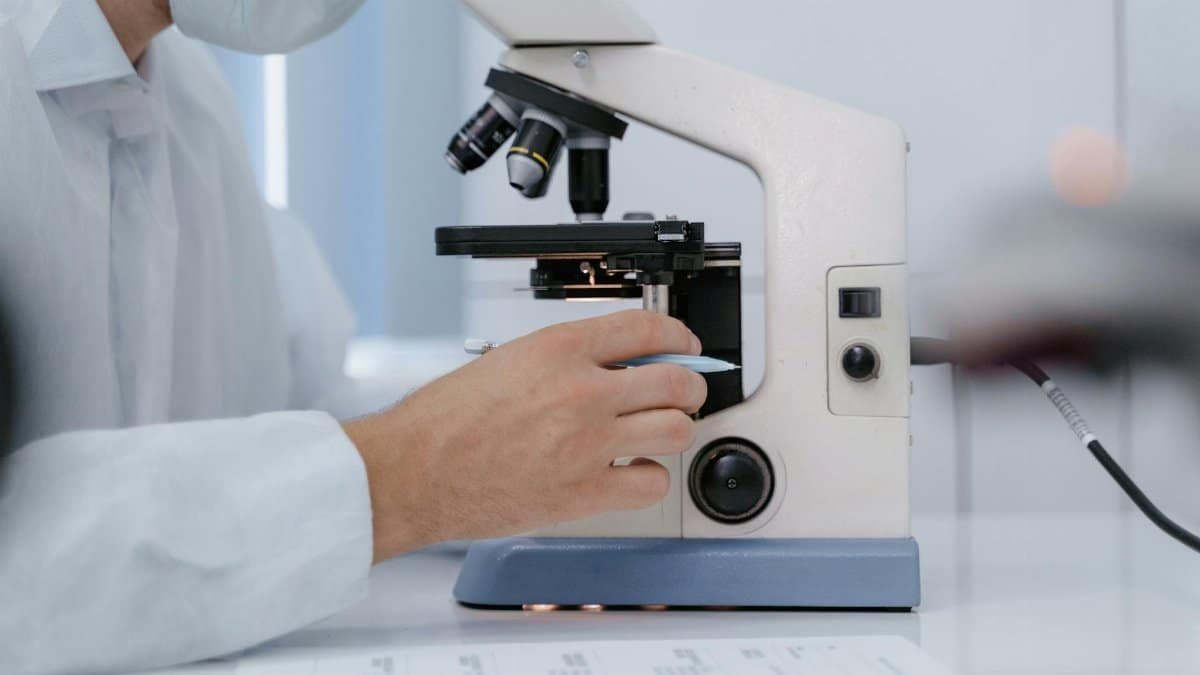 Researcher analyzing samples with a microscope in a lab setting.