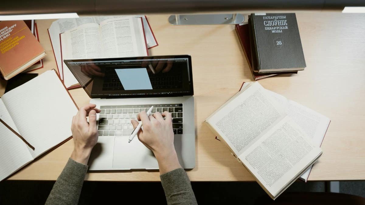 A student studies with a laptop and books, showcasing a learning environment.