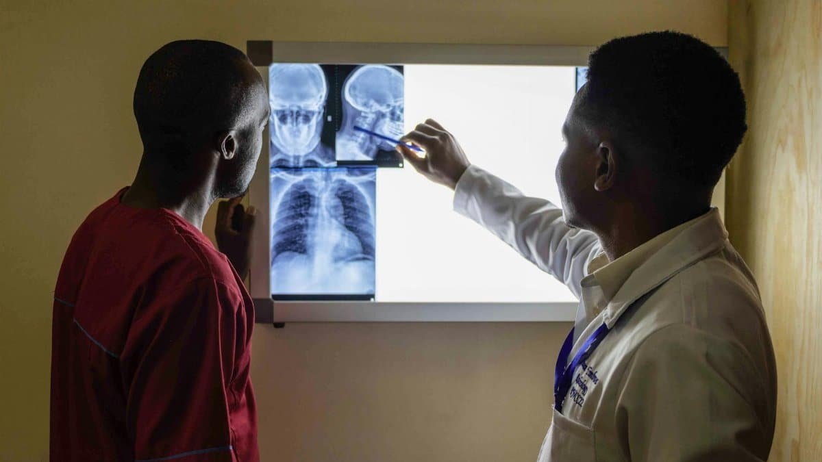 A doctor reviews X-ray images with a patient in a medical facility, highlighting healthcare interaction.