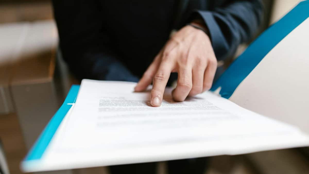 Close-up of a hand pointing at text on a business document in an office environment.