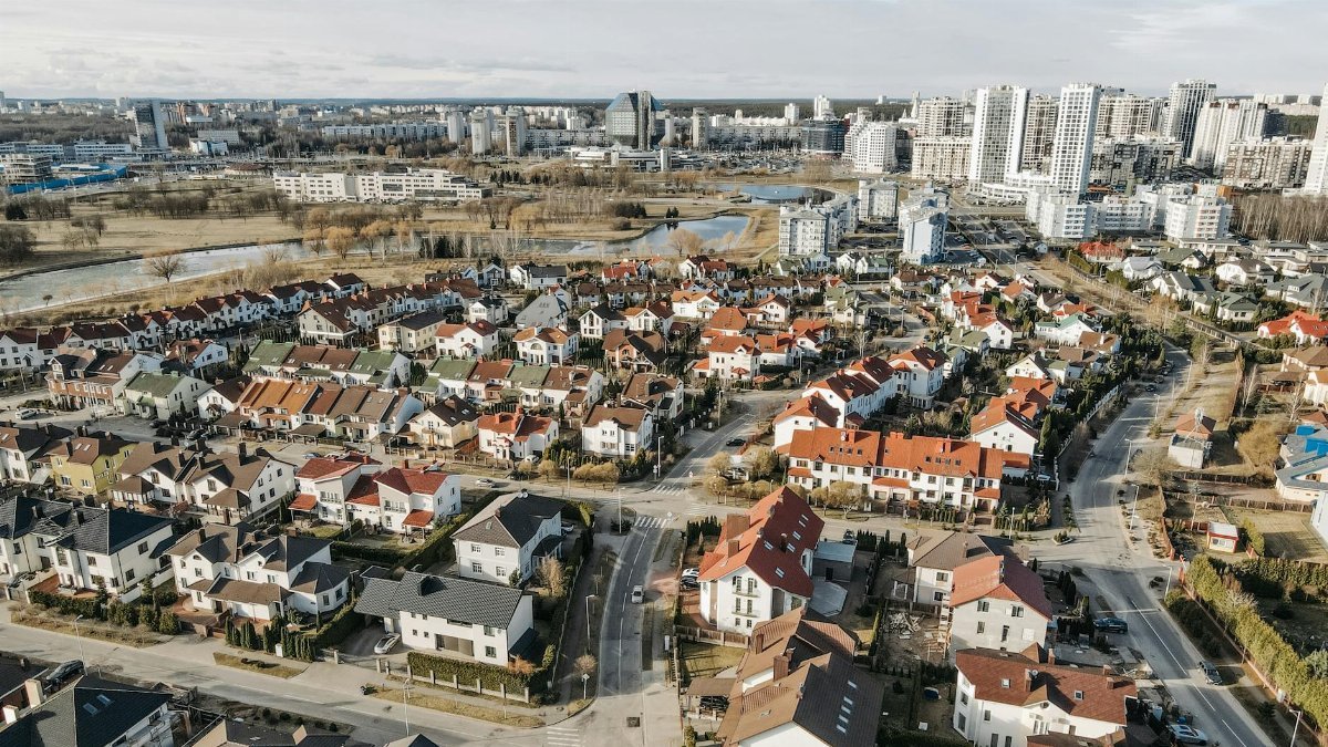Aerial perspective of suburban homes and urban high-rises, showcasing contrasting environments.
