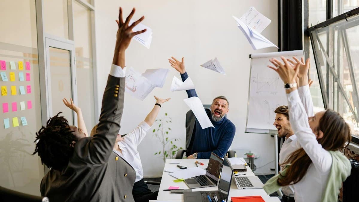 A diverse office team celebrating with papers in the air, showing teamwork and success.
