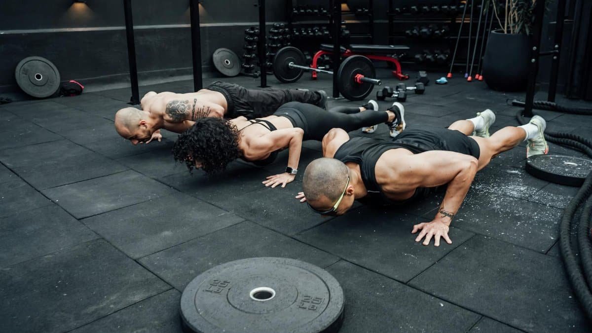 Fitness enthusiasts performing push-ups in a Mexico City gym. Emphasizing teamwork and strength.