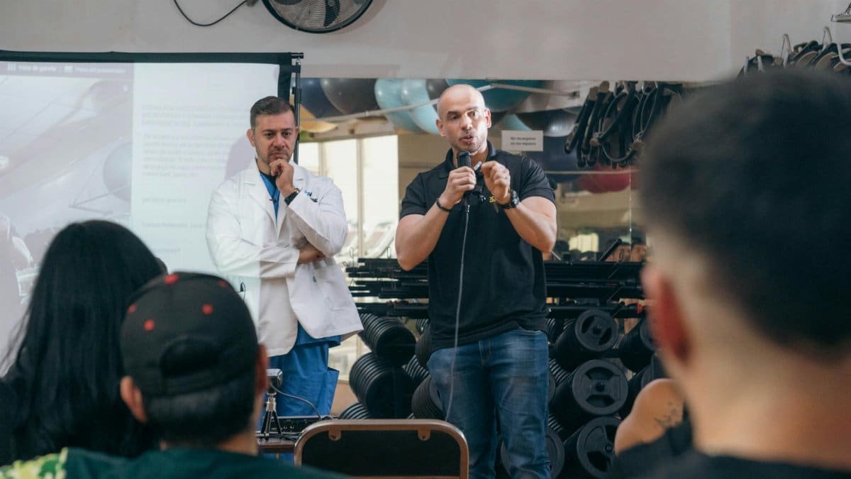 A doctor and fitness trainer conducting a seminar in a gym setting.