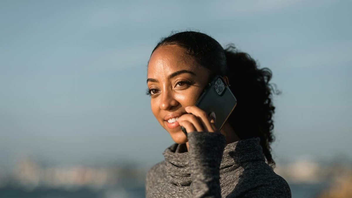 Young woman enjoying a phone call with a smartphone in a relaxed outdoor setting.