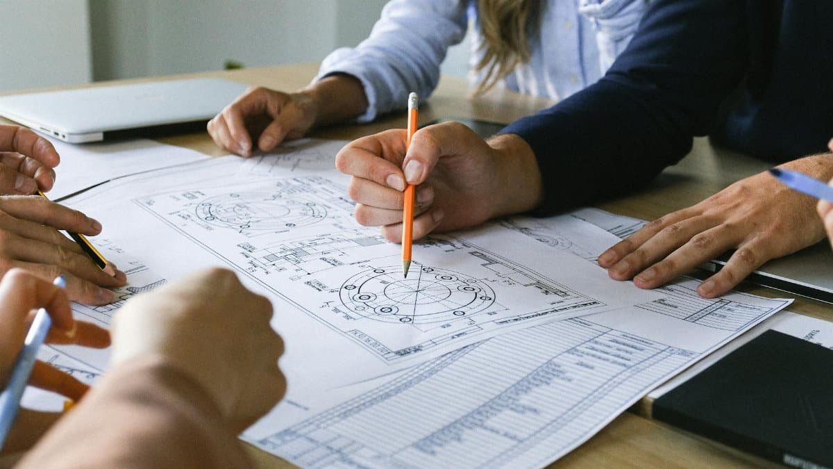 Group of crop anonymous colleagues gathering to discuss business project on papers at table