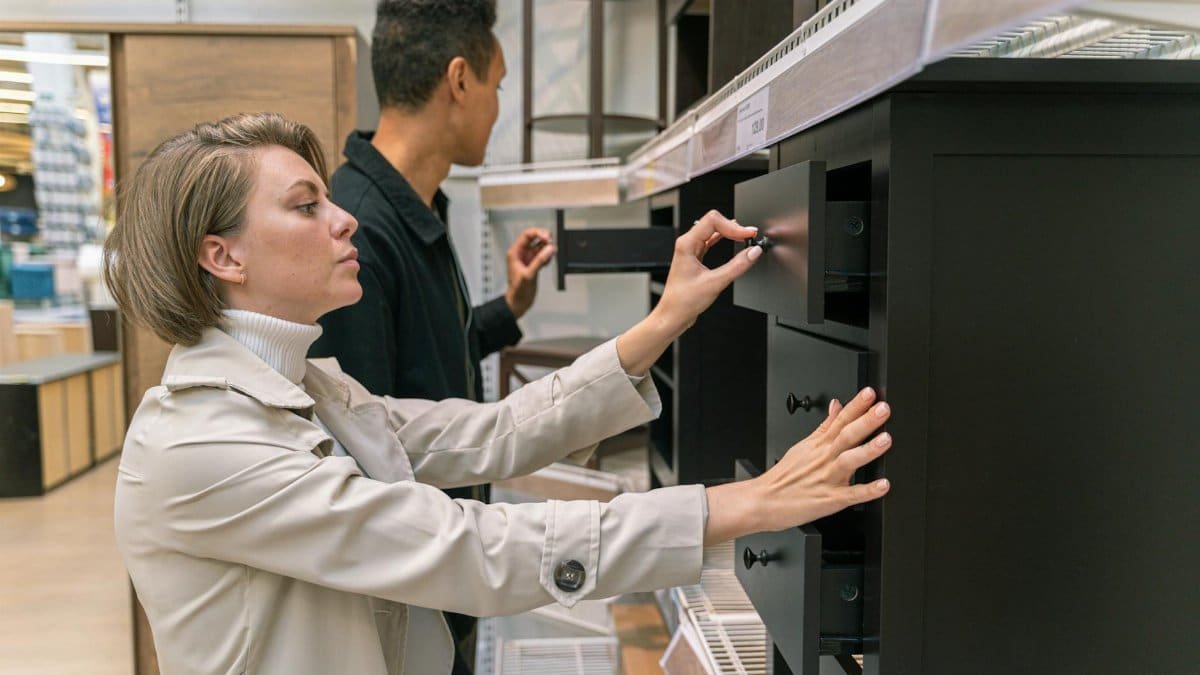 A man and woman examining drawers in a furniture store, exploring options.
