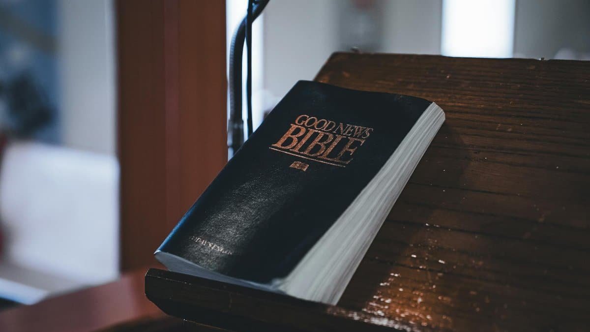 Close-up of the Good News Bible resting on a wooden lectern, ideal for religious themes.