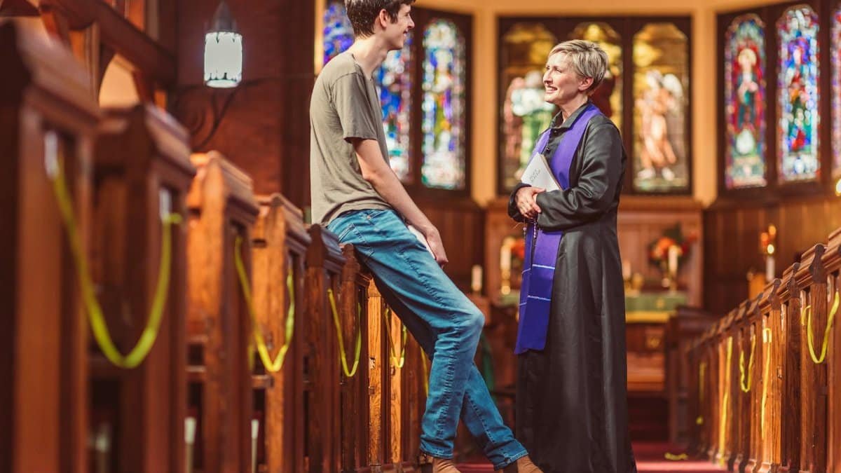 A pastor and parishioner having a friendly conversation inside a church.