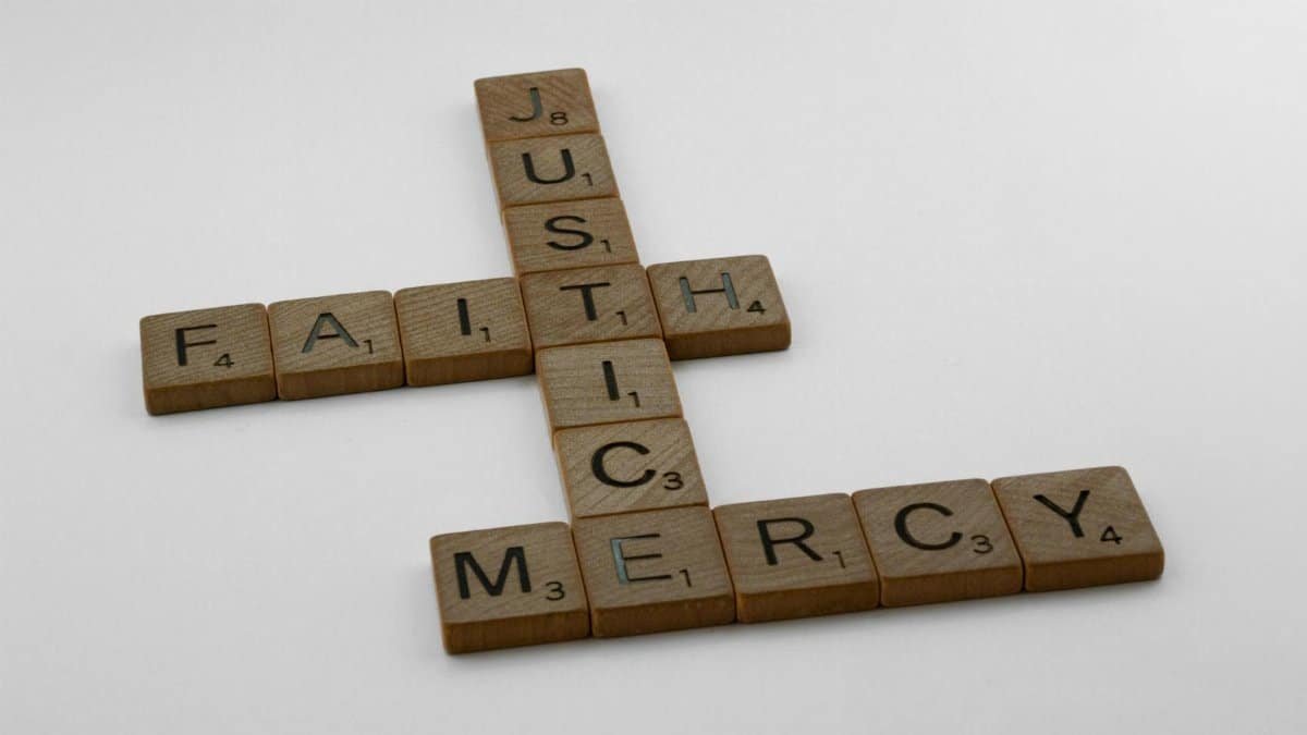 Scrabble tiles arranged to spell words like faith, justice, and mercy.
