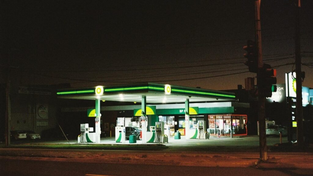 Illuminated BP gas station at night in Melbourne, showcasing urban life.