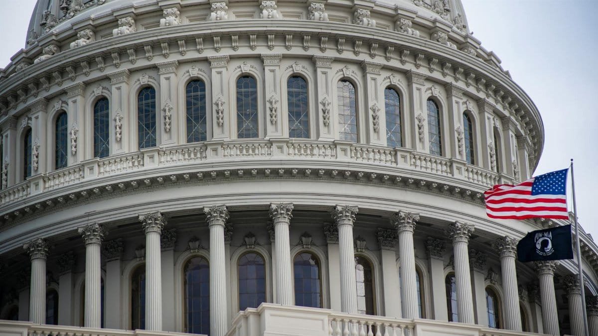 Detailed view of the US Capitol dome with the American flag flying nearby in Washington D.C.
